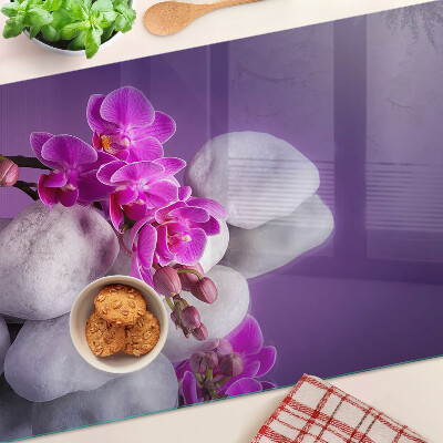 Skleněná deska do kuchyně Květy orchidejí na pozadí kamenů