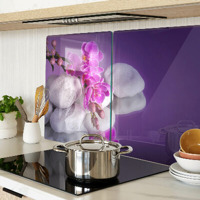 Skleněná deska do kuchyně Květy orchidejí na pozadí kamenů