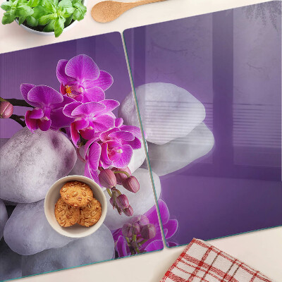 Skleněná deska do kuchyně Květy orchidejí na pozadí kamenů